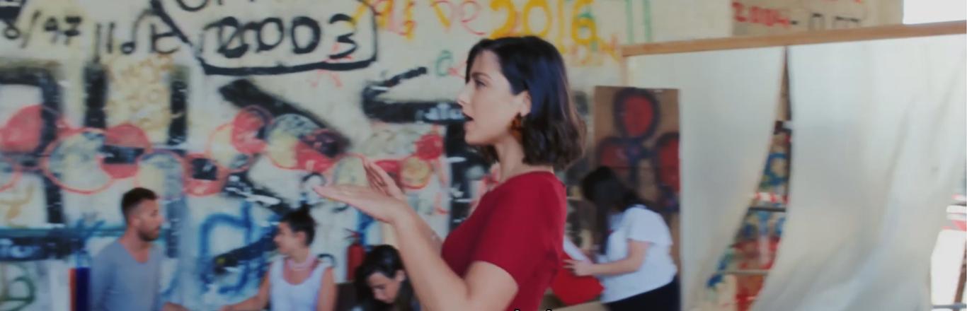 פריים של אישה בשמלה אדומה מהסרט "זוהר" של חני גל-עד - לחצו לפתיחת הסרטון בחלונית