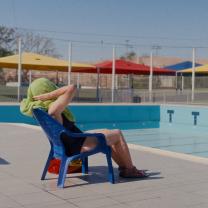 אישה משתזפת מול בריכה ריקה