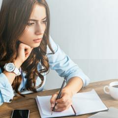 צעירה כותבת במחברת וחושבת