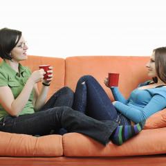 אילוסטרציה: שתי חברות משוחחות על ספב עם קפה ביד