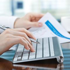 אילוסטרציה: אישה מקלידה במחשב ומחזיקה דפי חשבון