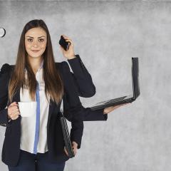 אישה מחזיקה מחשב, שעון, טלפון וזכוכית מגדלת