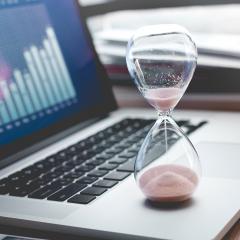 שעון חול מונח על מחשב נייד