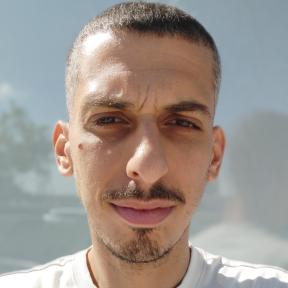 גבר מסתכל למצלמה עם חיוך בחולצה לבנה