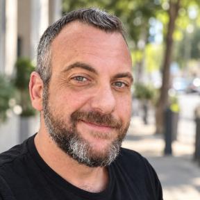 איש עומד ומחייך על רקע עצים