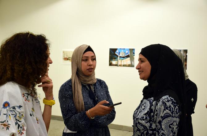 באסמה אבו חוטי משוחחת עם שתי צופות בתערוכה