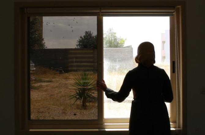 אישה ערביה מתסכלת בחלון בצילום מאחור