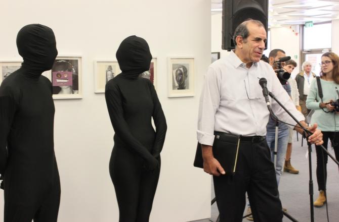 עו"ד גלעד שר יו"ר הועד המנהל בספיר ושתי דמויות בשחור בפתיחת התערוכה