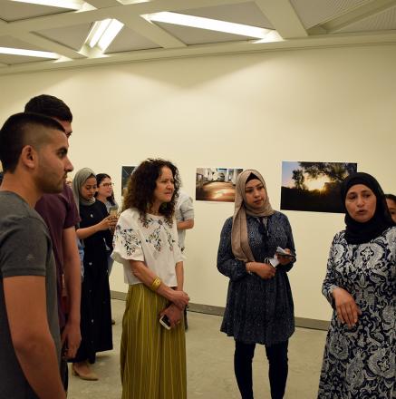 באסמה אבו חוטי מסבירה על צילומיה בפתיחת התערוכה
