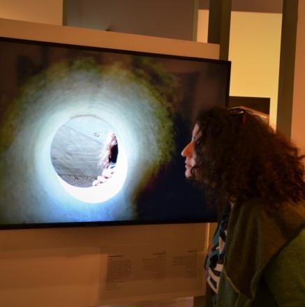 אישה צעירה מסתכלת במסך תלוי בצילום של חור הצצה