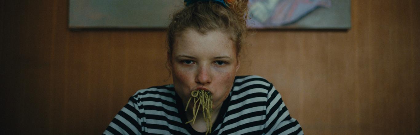 ילדה בחולצת פסים אוכלת פסטה