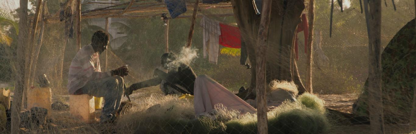 שני גברים יושבים תחת ציליית קש - לחצו לפתיחת הסרטון בחלונית