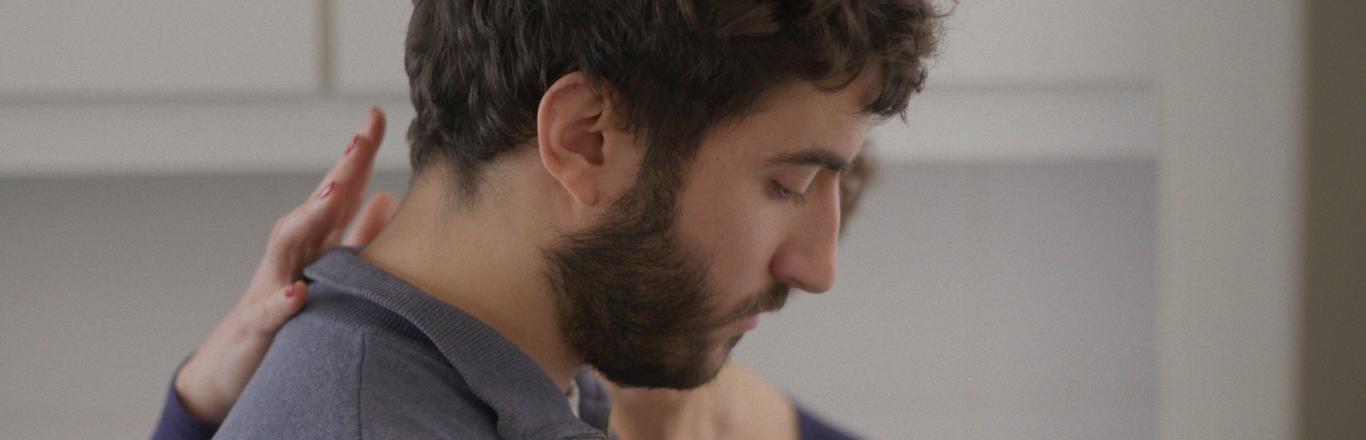 גבר עומד ויד של אישה טופחת לו על הגב - לחצו לפתיחת הסרטון בחלונית