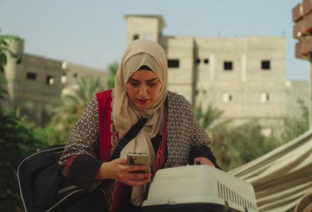 אישה עם כיסוי ראש מחזיקה כלוב של חתול