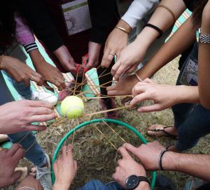 ידיים רבות במעגל אוחזות יחד חוטים וכדור טניס