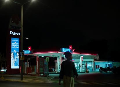 אישה עומדת מול תחנת דלק בלילה