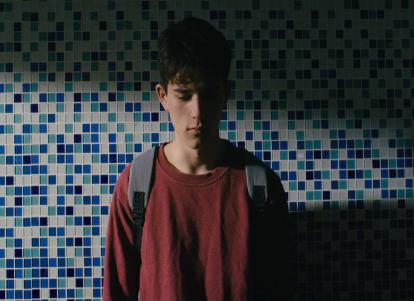 נער מול קיר פסיפס כחול בבריכה